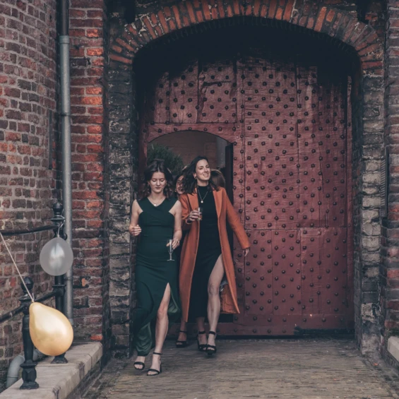 Twee vrouwen lopen naar buiten met een glas champagne